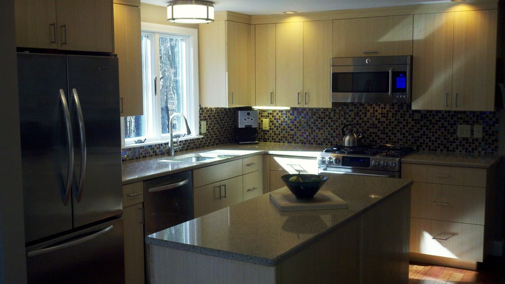 This kitchen has quartz countertops with a glass tile ...